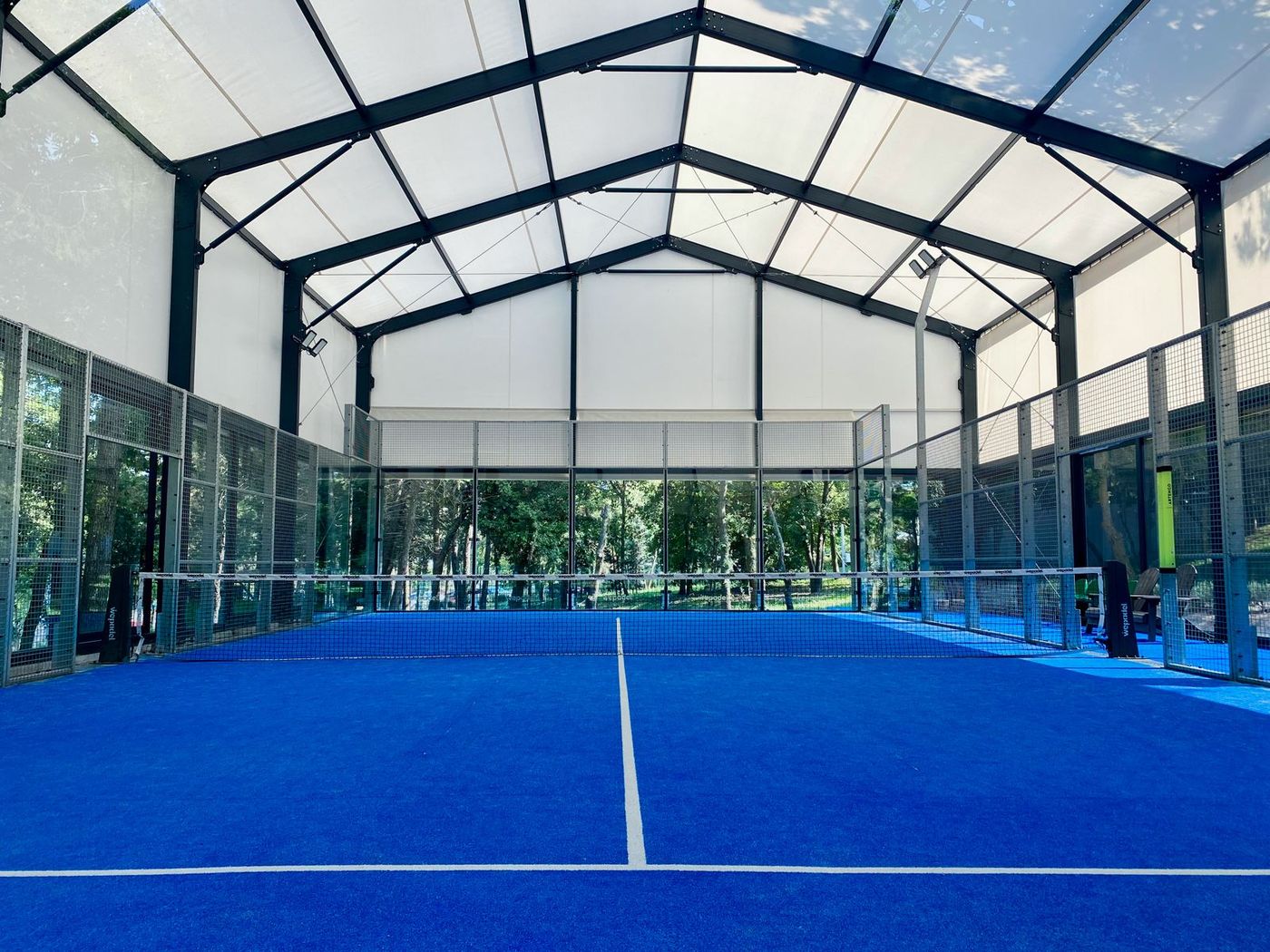Campo da padel coperto con superficie blu e pareti in vetro, immagine indicativa